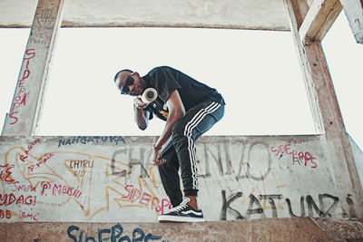 Full length of young man photographing against wall