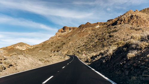 Road leading towards mountain against sky