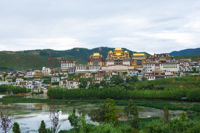 Temples by mountains against cloudy sky