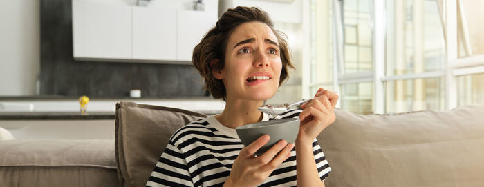 Young woman using mobile phone while sitting on sofa at home