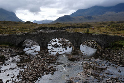 Arch bridge over mountains against sky