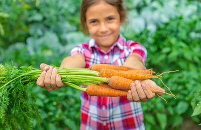 Portrait of girl holding carrots at farm