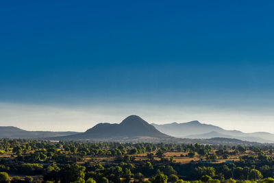 Scenic view of landscape and mountains against clear blue sky