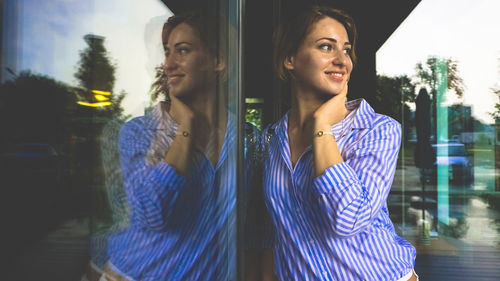 Smiling young woman reflecting on glass