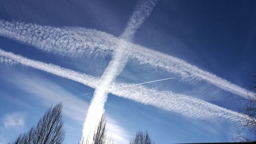 Low angle view of vapor trails in blue sky