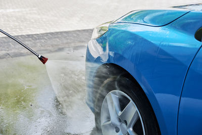 Cleaning car with high pressure water at car wash station
