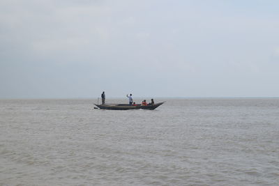 Men standing in sea against sky