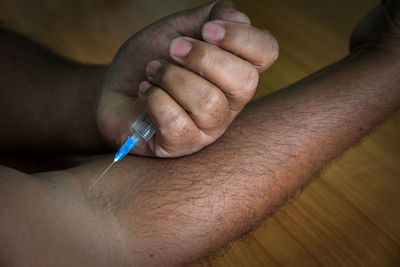 Cropped image of man injecting arm