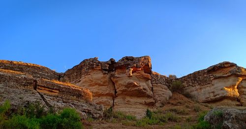 Rock formations on mountain against blue sky