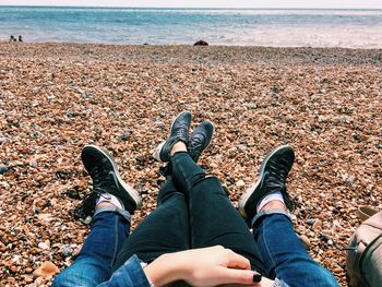 Low section of couple sitting on pebble beach