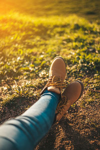 Low section of woman wearing shoes relaxing on field