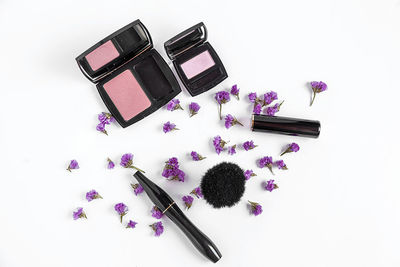Directly above shot of make-up products with flowers on white background