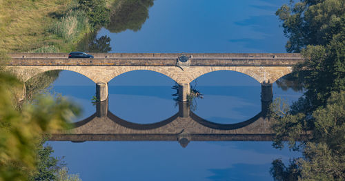 Arch bridge over river against sky