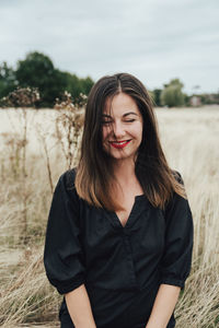 Portrait of smiling young woman standing on field