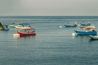 Fishing boats in sea against clear sky