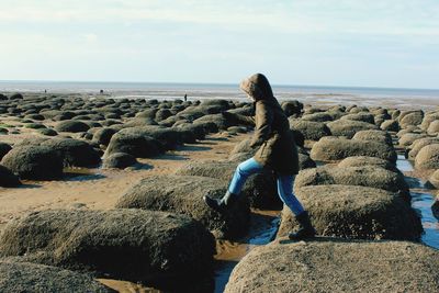 Woman walking at beach against sky