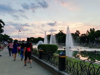 People at fountain against sky during sunset