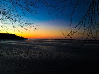 Scenic view of beach against sky at sunset
