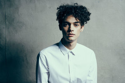 Portrait of young man standing against wall