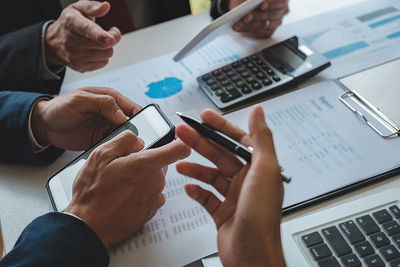 Midsection of man using smart phone on table