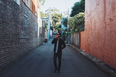 Young man in casuals walking on street while smoking cigarette