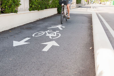Low section of person riding bicycle on sidewalk