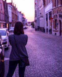 Rear view of woman standing on street at dusk