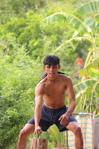 Rear view of young man standing against plants