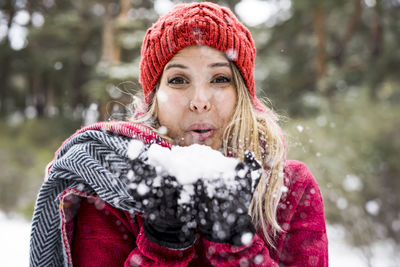 Close-up portrait of woman blowing snow