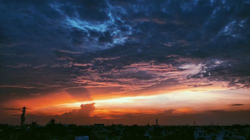 Silhouette trees and cityscape against sky during sunset