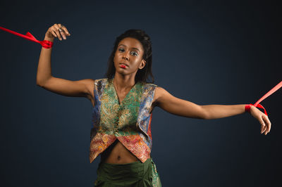 Portrait of young woman against black background