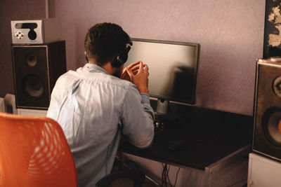 Concentrated man listening music on headphones sitting by computer