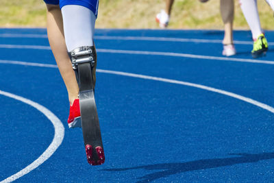 Low section of athlete with artificial limb running on track