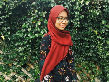 Portrait of smiling woman standing against plants