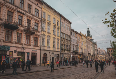 People walking on street against buildings in city