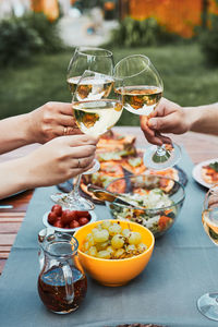 Family and friends having meal - pizza, salads, fruits and drinking white wine during summer picnic