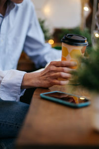 Midsection of woman with cup of coffee, using laptop on table