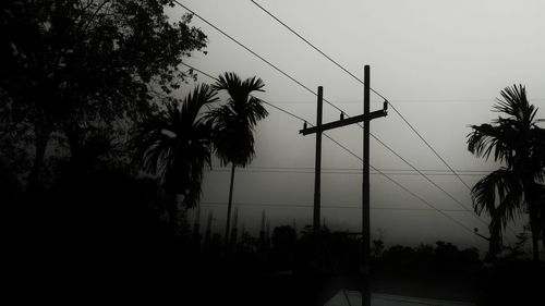 Low angle view of silhouette electricity pylon against sky