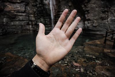 Cropped hand against waterfall