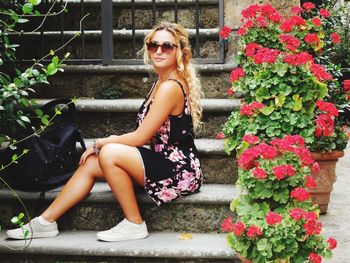 Portrait of smiling woman sitting by potted plant