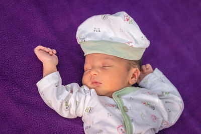 Newborn baby isolated sleeping in white cloth with purple background from different angle
