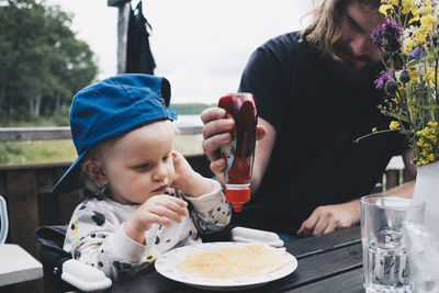 Girl looking at father squeezing honey on waffles at table