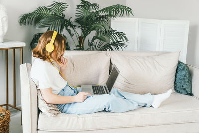 Young woman sitting on sofa at home