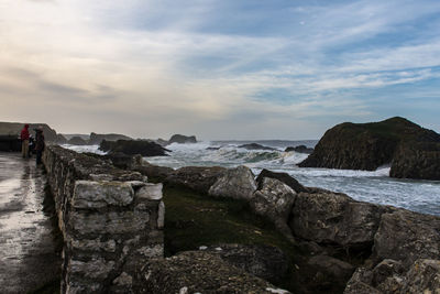 Rocky sea shore against cloudy sky