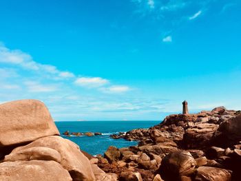 Rock formations by sea against blue sky