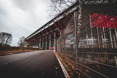 Empty road by building against sky