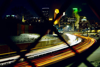 Light trails on road amidst buildings in city at night