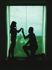 Silhouette of people standing against window