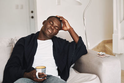 Man with coffee cup sitting on sofa at home