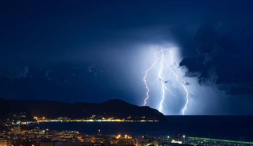 Lightning over illuminated cityscape against sky at night